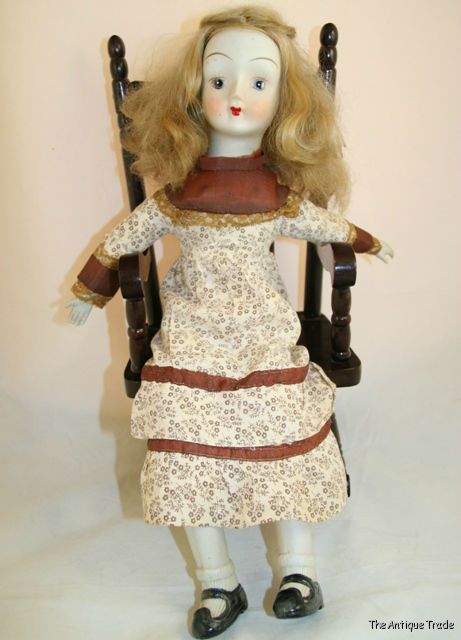 Vintage British bisque and stuffed body doll on wooden rocking chair